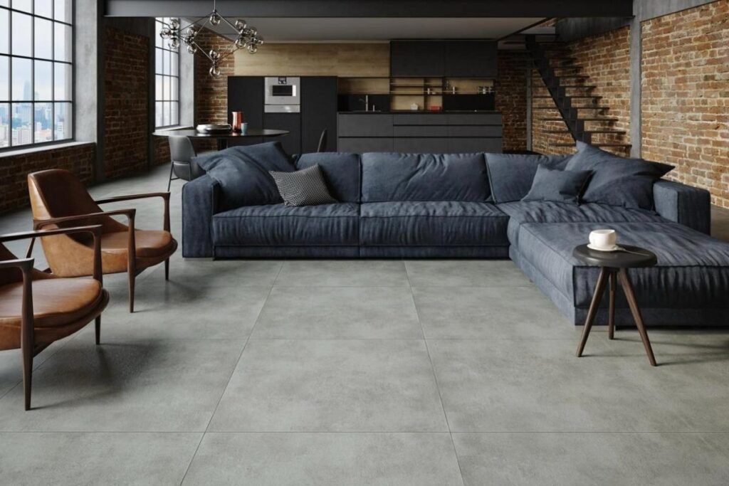 Sala de estar moderna com piso de cimento queimado, sofá, mesa de centro de madeira e plantas, iluminada por luz natural.