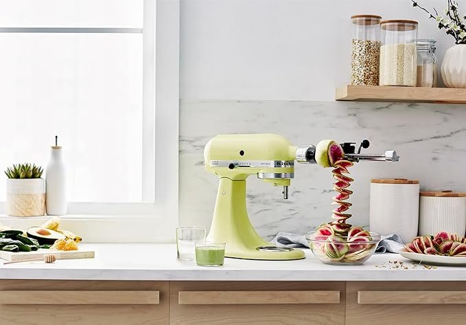 Batedeira KitchenAid Artisan com acessórios inclusos organizados sobre a bancada de uma cozinha moderna.