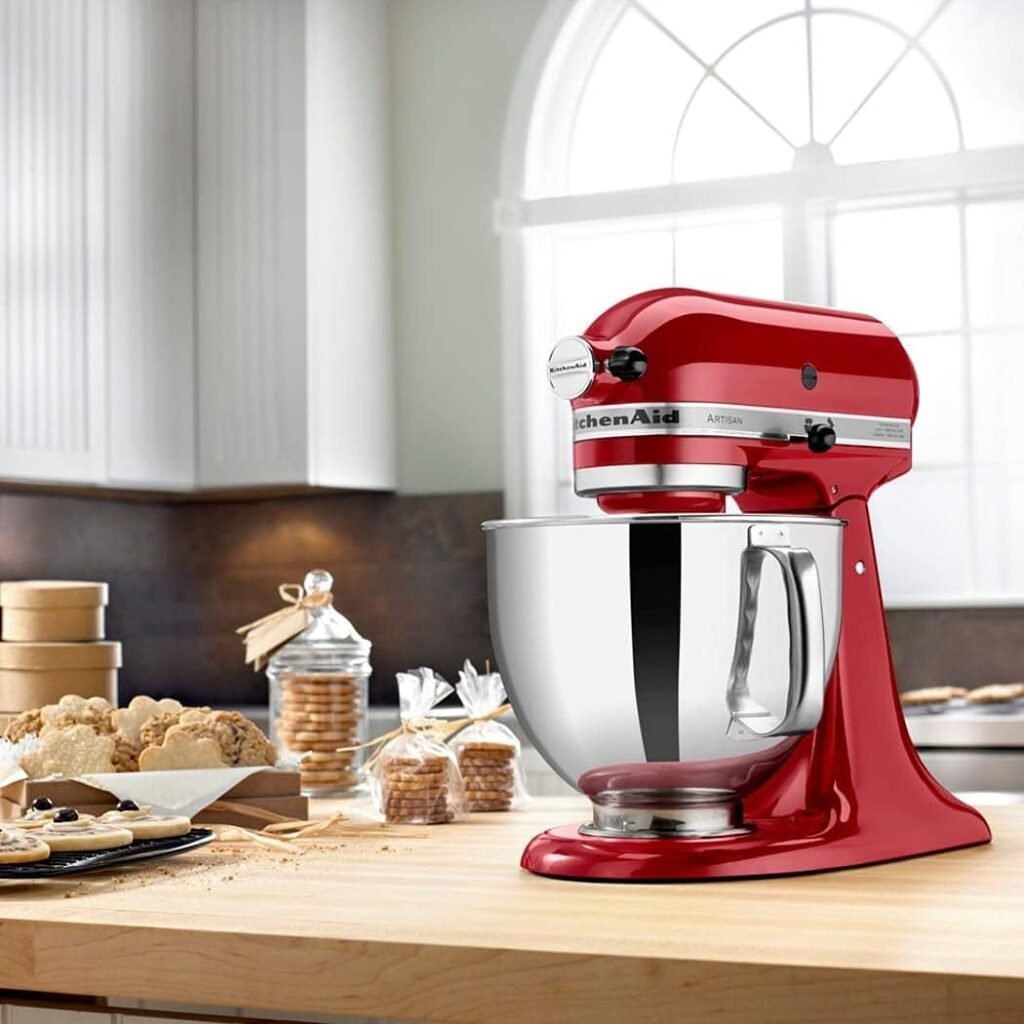 Batedeira KitchenAid Artisan vermelha sobre bancada de cozinha moderna e iluminada.